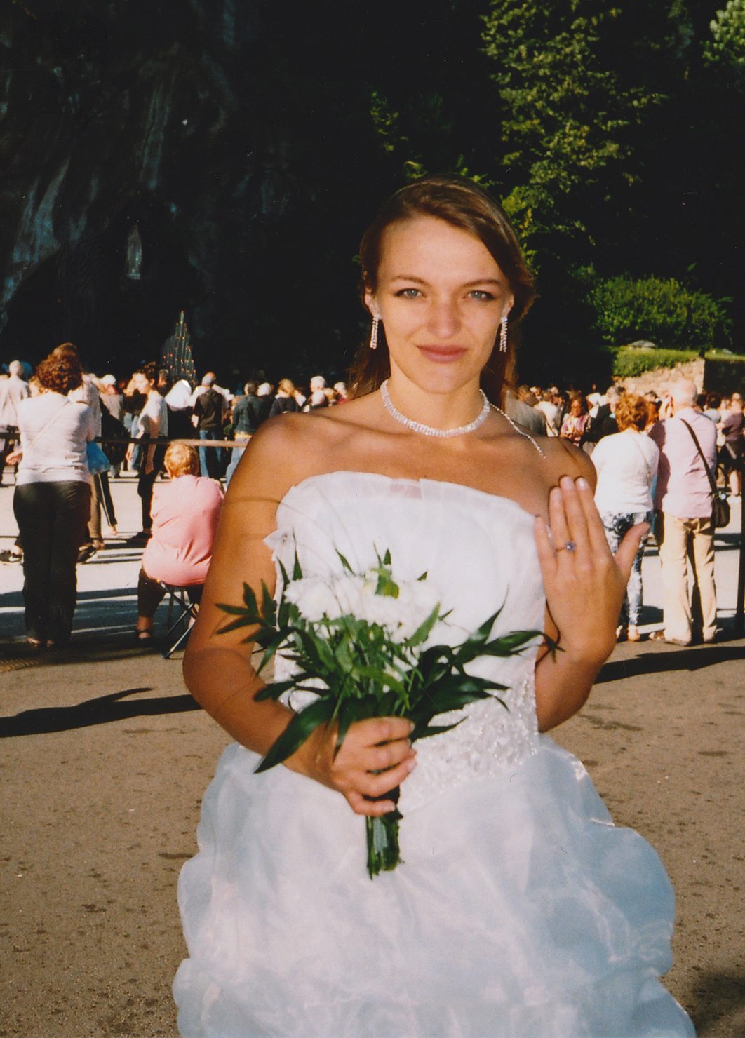 Éva Ostrowska showing the ring, bouquet in hand, among pilgrims at the Grotto of Lourdes, 2016