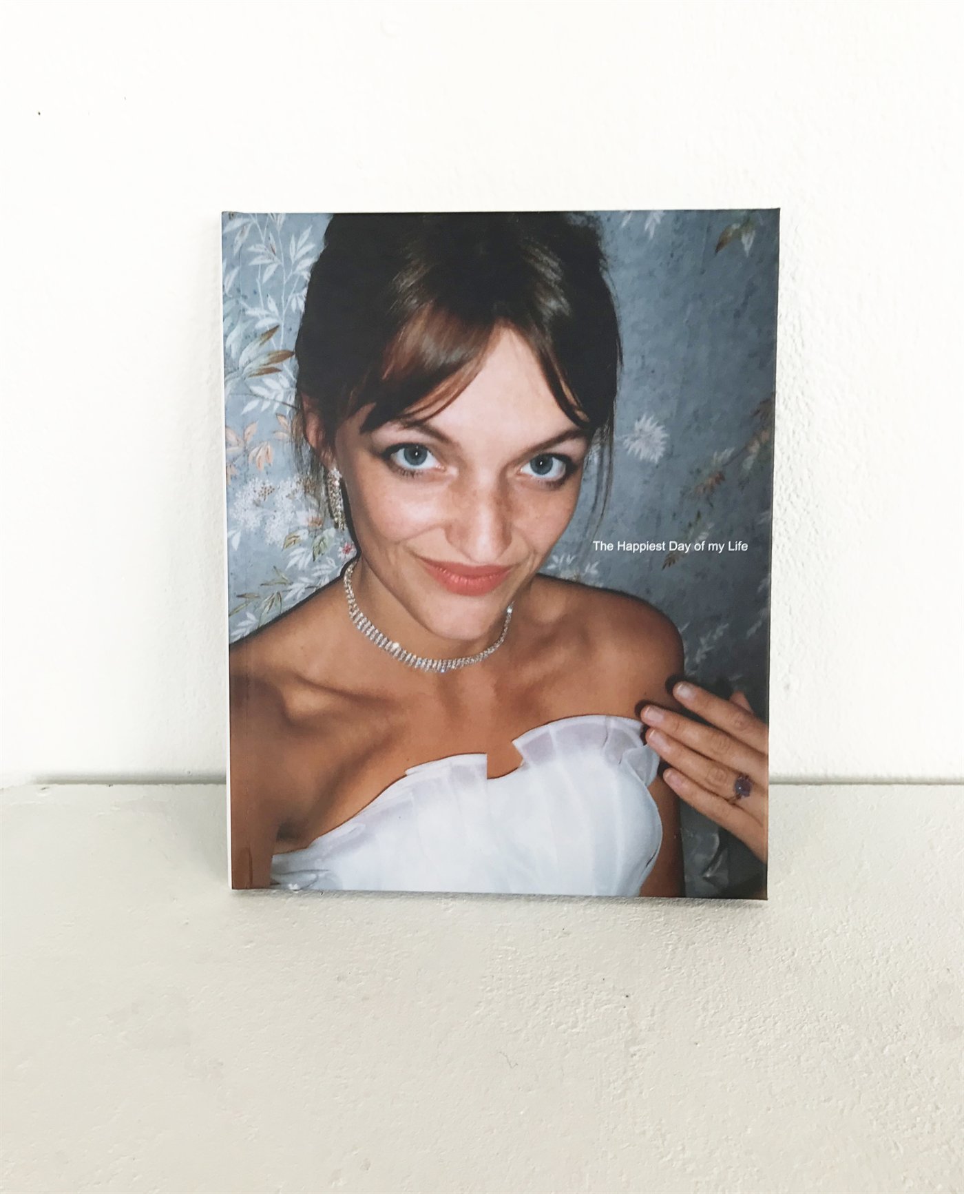 Eva Ostrowska, The Happiest Day of My Life, artist book on her self-marriage at Lourdes, analogue and digital photography, edition of 50, 2016, cover showing the bride in a white dress against floral wallpaper