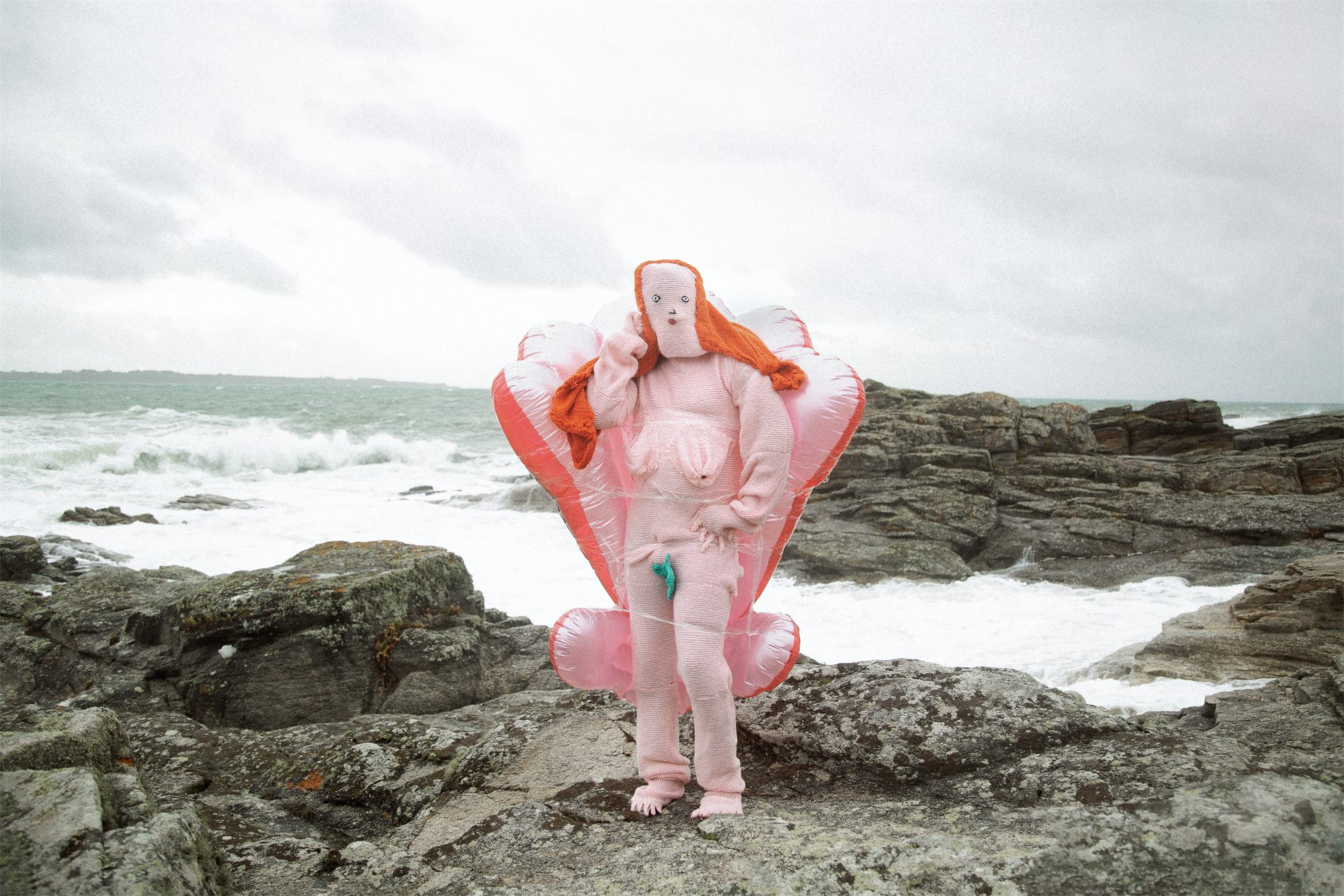 Éva Ostrowska, Venus, pink knitted costume with inflatable shell on grey sea rocks, photographic performance