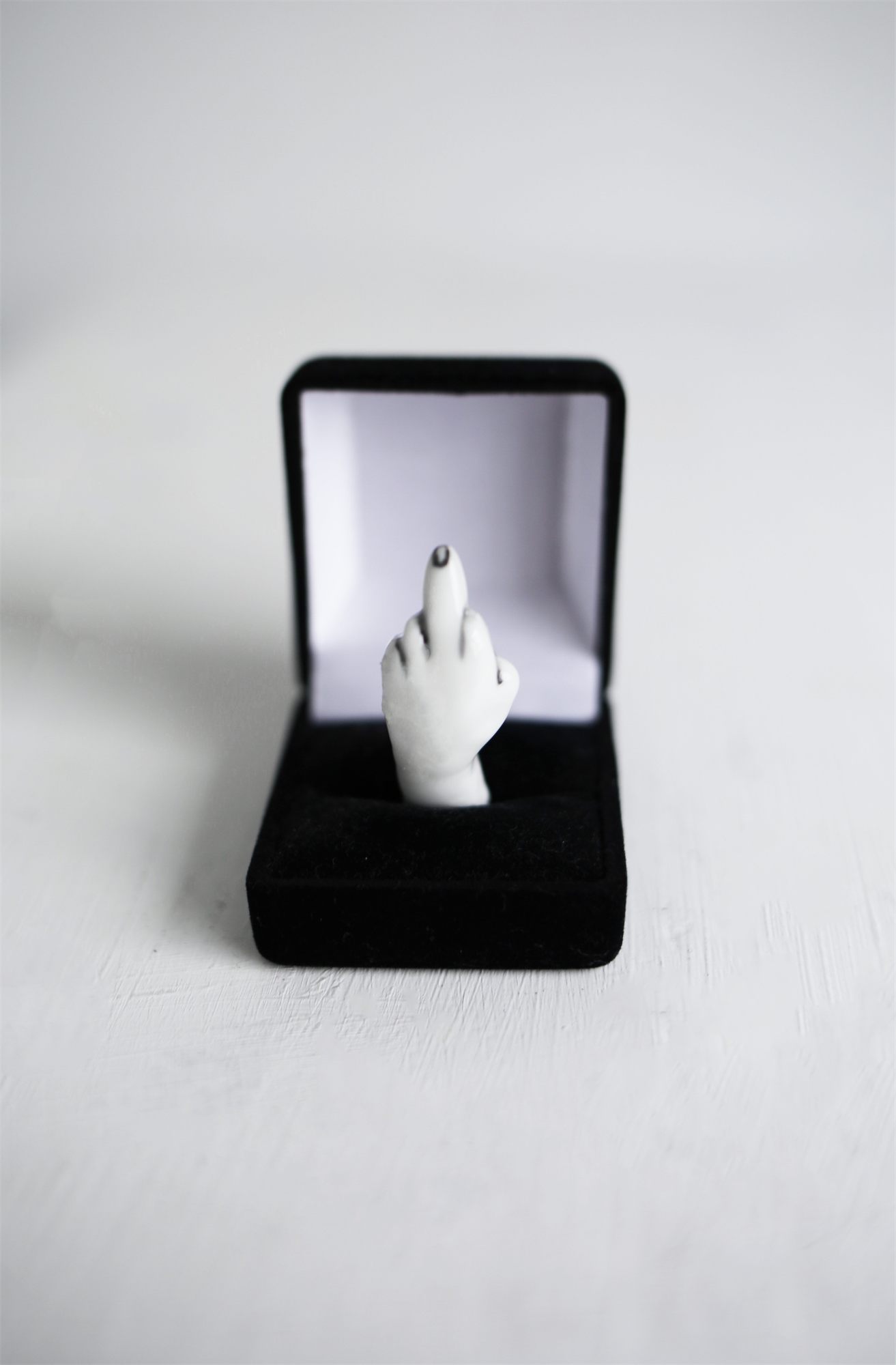 Eva Ostrowska, Will You Marry Me, porcelain hand raising the middle finger in a black velvet ring box, 2019